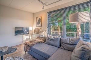 uma sala de estar com um sofá e uma grande janela em Zee van Tijd em De Koog