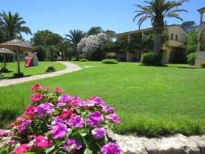 a garden with pink flowers in front of a building at Hotel Costa dei Fiori in Santa Margherita di Pula