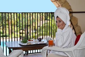 a woman sitting in a chair with a plate of food at Hotel Costa dei Fiori in Santa Margherita di Pula