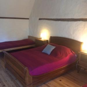a bedroom with two beds with red sheets and two lamps at Aveyron West in Saint-Igest