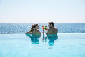 a man and a woman in the water with beach balls at Hotel Costa dei Fiori in Santa Margherita di Pula