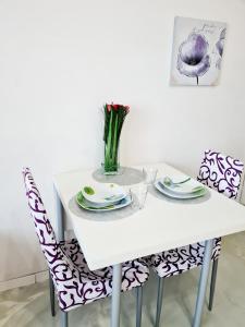einen weißen Tisch mit zwei Stühlen und eine Vase Blumen in der Unterkunft Minisuite in Bologna