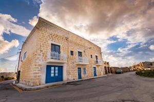 a brick building with blue doors on a street at Fiftyfour West Boutique Living in Għarb
