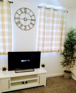 a flat screen tv sitting on a stand in a living room with a clock at Sigma Central Apartment 2 in North Shields