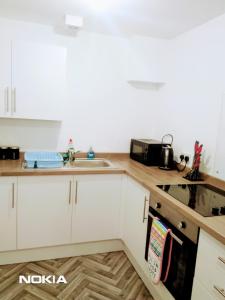 a kitchen with white cabinets and a sink at Sigma Central Apartment 2 in North Shields +17 photos