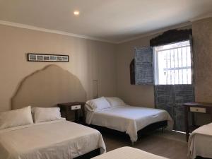 a room with two beds and a window at Hotel Galeria la Trinidad in Cartagena de Indias