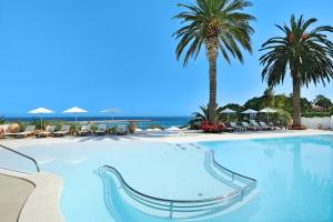 a large swimming pool with palm trees and chairs at Le Calette Bay in Cefalù