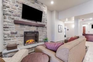 a living room with a stone fireplace with a tv at Cobblestone Inn & Suites - Holdrege in Holdrege