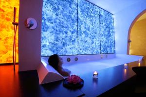 a woman laying in a bath tub in a room at Le Calette Bay in Cefalù