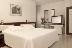 a white bedroom with a white bed and a television at CHA Prime Curitiba in Curitiba