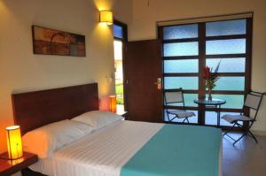 a bedroom with a bed and a balcony with a table and chairs at Brizantha Hotel Campestre in Villavicencio