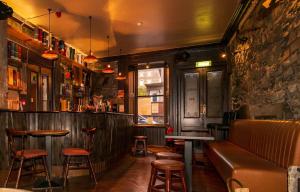 um bar com um sofá e algumas mesas e cadeiras em The Whisky Vaults em Oban mais 37 fotografias
