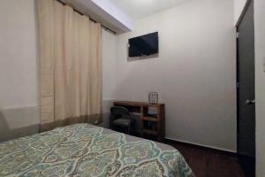 Schlafzimmer mit einem Bett, einem Schreibtisch und einem TV in der Unterkunft Embajadoras Apartment & Rooftop in Guanajuato