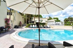 - une piscine avec un parasol et des chaises dans l'établissement LaPlaya 101E-Relax on your private lanai under the palms!, à Longboat Key