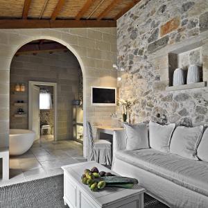 sala de estar con sofá y pared de piedra en Relais Masseria Capasa, en Martano