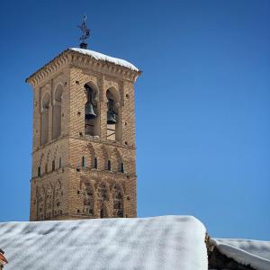 a clock tower with bells on it in the snow at La Casa de Jabe - Toledo Casco Antiguo in Toledo