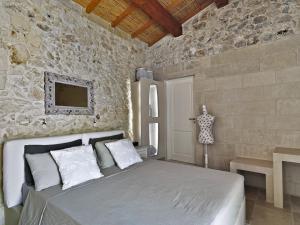 1 dormitorio con cama y pared de piedra en Relais Masseria Capasa, en Martano