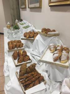 una tavola ricoperta di vassoi di prodotti da forno e ciambelle di Hotel Verri a Misano di Gera dʼAdda