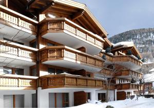 a building with wooden balconies in the snow at Apartment Everest in Zermatt
