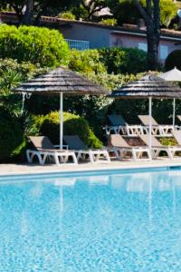 una piscina con sombrillas y sillas junto a una piscina en Le village de l'hacienda - Marina di santa Giulia- Porto-Vecchio, en Porto Vecchio