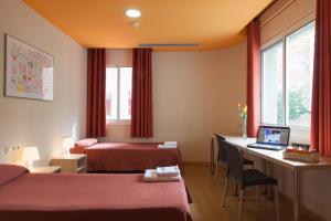 een hotelkamer met 2 bedden en een bureau met een laptop bij Residència Erasmus Gracia in Barcelona