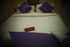 a large white bed with purple pillows and a sign on it at Reunion Villa in Udupi