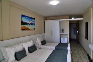 a hotel room with two beds and a painting on the wall at Hotel Costa do Atlantico in Natal