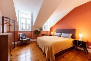 a bedroom with orange walls and a bed and a chair at Contador Mor Rooms and Apartments in Lisbon