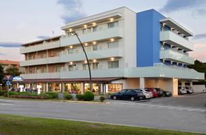 a large building with cars parked in a parking lot at Alla Pergola in Bibione