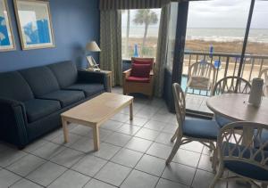 uma sala de estar com um sofá, uma mesa e cadeiras em Ocean Club Resort Myrtle Beach a Ramada by Wyndham em Myrtle Beach