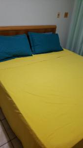 a yellow bed with two blue pillows on it at Aquaville - Porto das Dunas in Aquiraz