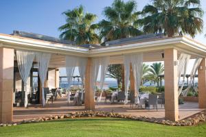 a pavilion with tables and chairs and palm trees at Insotel Punta Prima Resort in Punta Prima