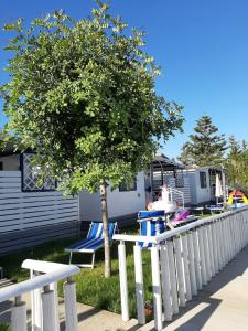 a fence with chairs and a tree in front of a caravan at Campeggio Praia Mare in Campofelice di Roccella