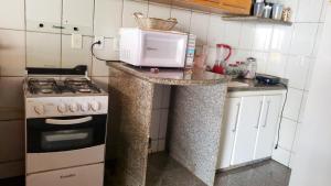 a kitchen with a stove and a microwave on a counter at Oncotô Palmas Hostel in Palmas