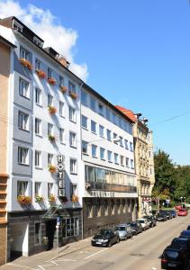 un gran edificio blanco en una calle de la ciudad con coches aparcados en Central-Classic Hotel en Stuttgart