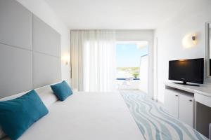 a white bedroom with a large bed and a television at Insotel Hotel Formentera Playa in Playa Migjorn