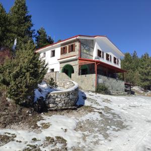 a house on a hill with snow in front of it at Koromilia refuge in Díon