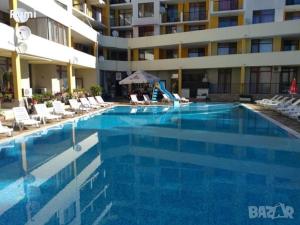 a large blue swimming pool with chairs and a building at Blue Summer in Sunny Beach