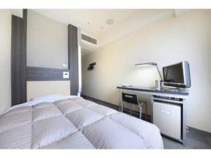 um quarto com uma cama e uma secretária com uma televisão em R & B Hotel Kamata Higashiguchi - Vacation STAY 14841v em Tóquio