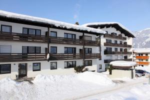 een met sneeuw bedekt gebouw met een berg sneeuw ervoor bij Appartement Panoramablick in Brixen im Thale