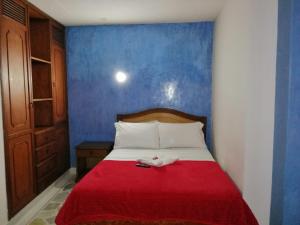 a bed with a red blanket and a blue wall at HOTEL YORYTANIA BOUTIQUE in Pitalito