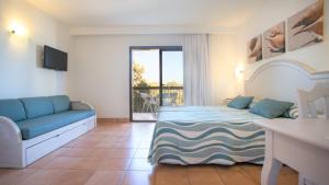 a bedroom with a bed and a couch and a balcony at Insotel Hotel Formentera Playa in Playa Migjorn
