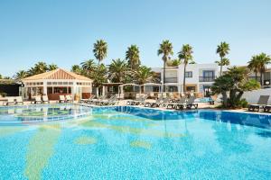 a large swimming pool with chairs and palm trees at Insotel Hotel Formentera Playa in Playa Migjorn +28 photos