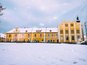 um edifício amarelo com neve no chão em Wellness hotel Rezidence em Nové Hrady