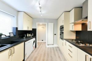 una cucina con armadietti bianchi e ripiani neri di 4 Bedroom, 2 bathroom house - Free Parking a Pontefract