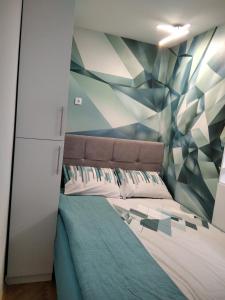 a bedroom with a bed with a geometric wall at Apartman Lana in Bijeljina