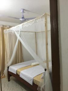 Bett mit Baldachin in einem Zimmer in der Unterkunft Brink Breeze Guest Rooms & Apartments in Mombasa