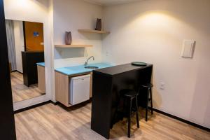 eine Küche mit einer Spüle und einer Theke mit Hockern in der Unterkunft Hotel Executive Arrey in Teresina