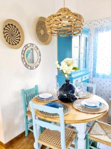 una sala da pranzo blu e bianca con tavolo e sedie in legno di Villa Arbocers a Cala Blanca