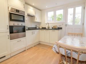 a kitchen with white cabinets and a table at Puffin Cottage in Truro